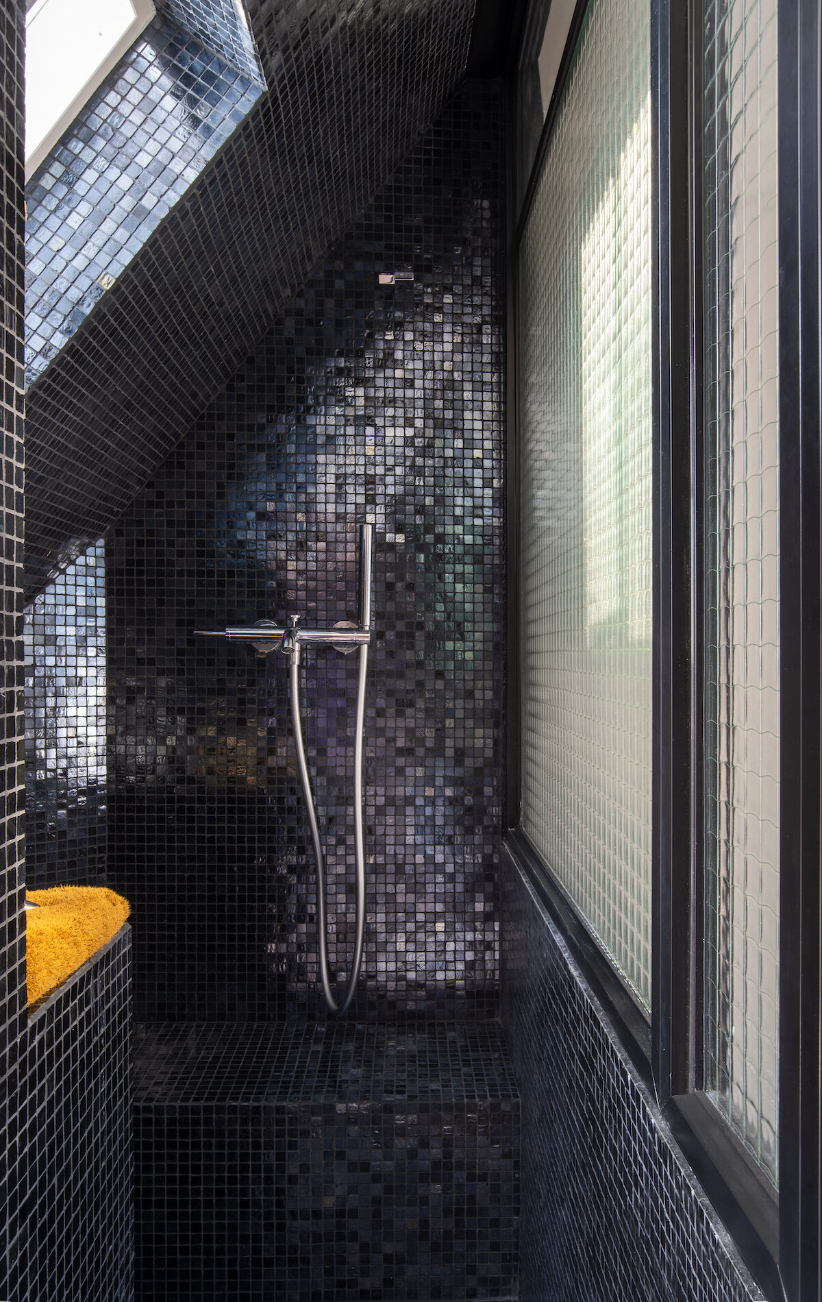 Salle d’eau avec mosaïque noire dans un studio rénové de 12 m²