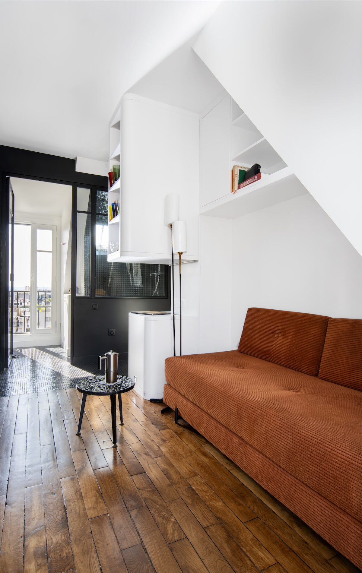 Aménagement d’un studio de 12 m² avec canapé orange et mobilier sur mesure